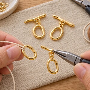 Gold-tone brass oval toggle clasps. Example of handling the component; tools are not included. ring 20 x 12.5mm; T-bar 23.8mm. Buyer pack: 4 complete clasp sets.