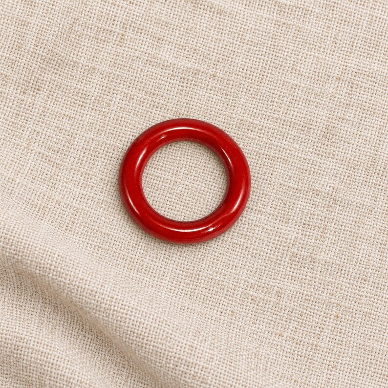 Red closed metal ring sample on natural linen; one selected colour option.