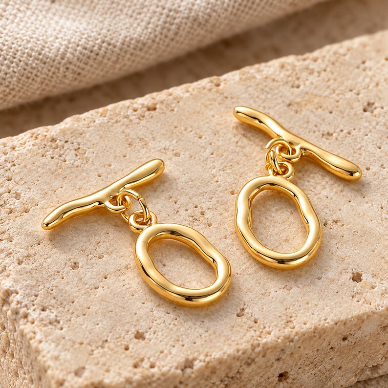 Gold-tone brass oval toggle clasps. Macro detail. ring 20 x 12.5mm; T-bar 23.8mm. Buyer pack: 4 complete clasp sets.