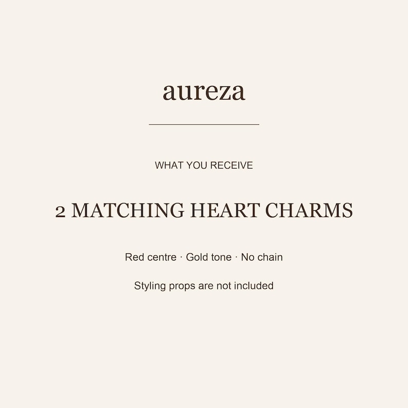 K&ouml;nnte beinhalten: Eine Produktinformationskarte mit dem Text aureza, WHAT YOU RECEIVE, 2 MATCHING HEART CHARMS, Red centre, Gold tone, No chain und Styling props are not included. Der Hintergrund ist ein einfarbiger, heller Cremeton mit dunkelbraunem Text.