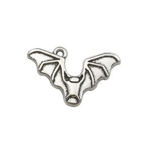 May include: A silver-toned metal bat charm featuring a stylized design with outstretched wings and a small circular loop at the top for attachment. The surface has recessed detailing to define the bat's facial features and wing structure.