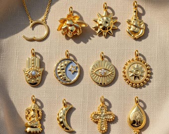 May include: A collection of gold-colored pendants featuring various designs, including a sun, lotus flower, Hamsa hand, moon and star, and an eye. The pendants are displayed on a neutral-colored surface, showcasing their intricate details and reflective surfaces.