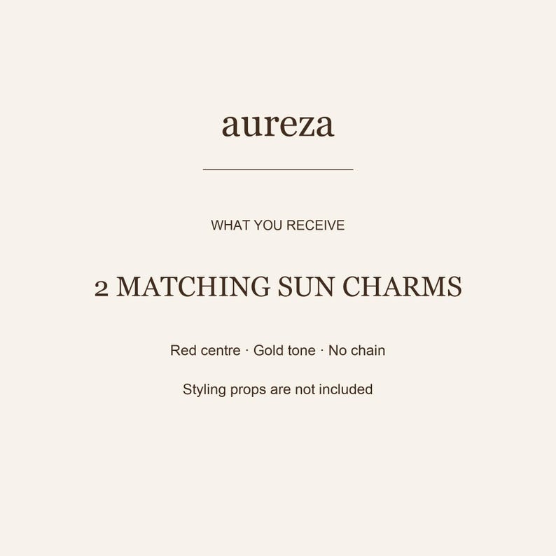 May include: A product information card with the text aureza, WHAT YOU RECEIVE, 2 MATCHING SUN CHARMS, Red centre, Gold tone, No chain, and Styling props are not included. The text is dark brown on a light cream background with a horizontal line.