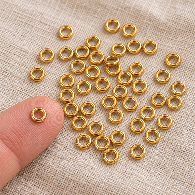 Gold-tone stainless steel closed jump rings. Scale reference preview. 4mm outer diameter; 1.2mm wire. Buyer pack: 50 pieces.
