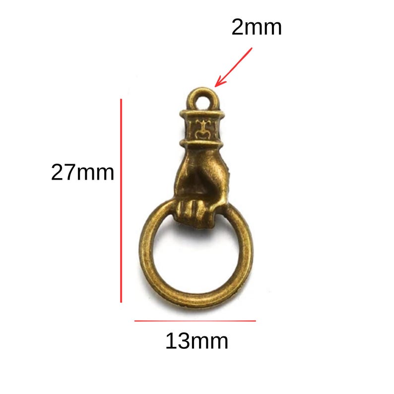 May include: Antique bronze-colored charm featuring a hand holding a ring. The charm measures 27mm in length, 13mm in width, and has a 2mm loop. This decorative charm is suitable for jewelry making and crafting projects.