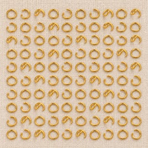 Gold-tone stainless steel open jump rings. Pack flat lay; quantity check pending. 5mm diameter; 0.8mm wire. Buyer pack: 100 pieces.