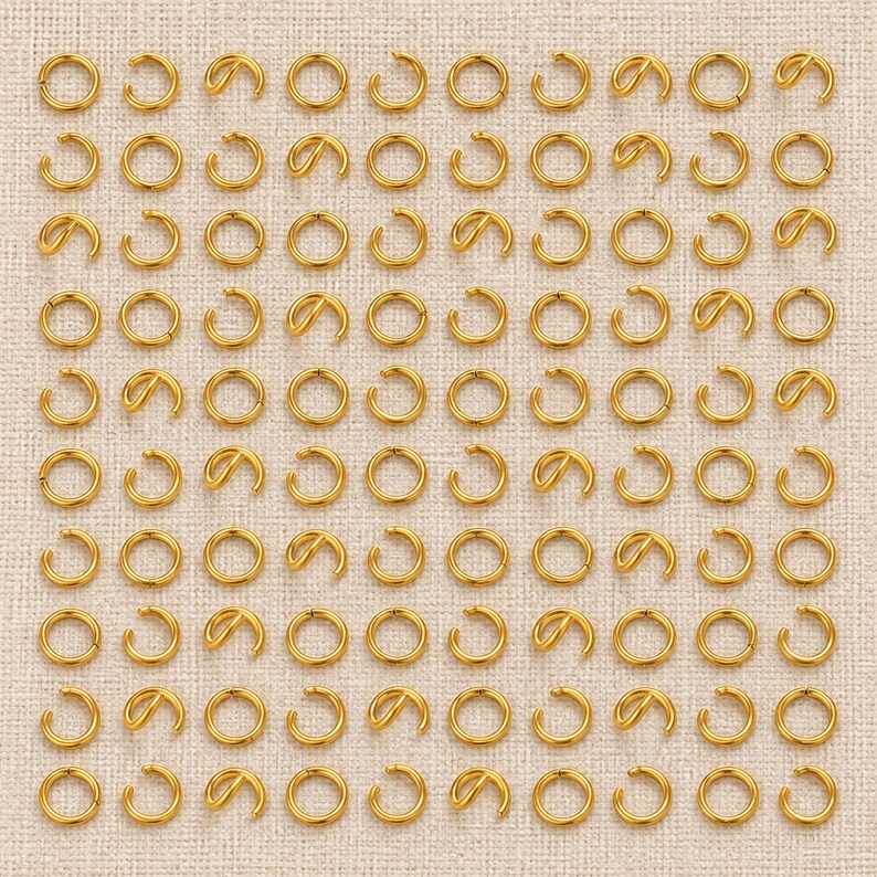 Gold-tone stainless steel open jump rings. Pack flat lay; quantity check pending. 5mm diameter; 0.8mm wire. Buyer pack: 100 pieces.