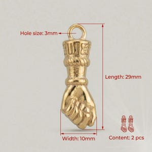 May include: A gold-colored fist-shaped charm with a loop at the top for hanging. The charm is 29mm long, 10mm wide, and has a 3mm hole. The image also shows the content is 2 pieces.