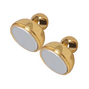 Two authentic matching gold-tone magnetic halves separated to show their flat circular contact faces.