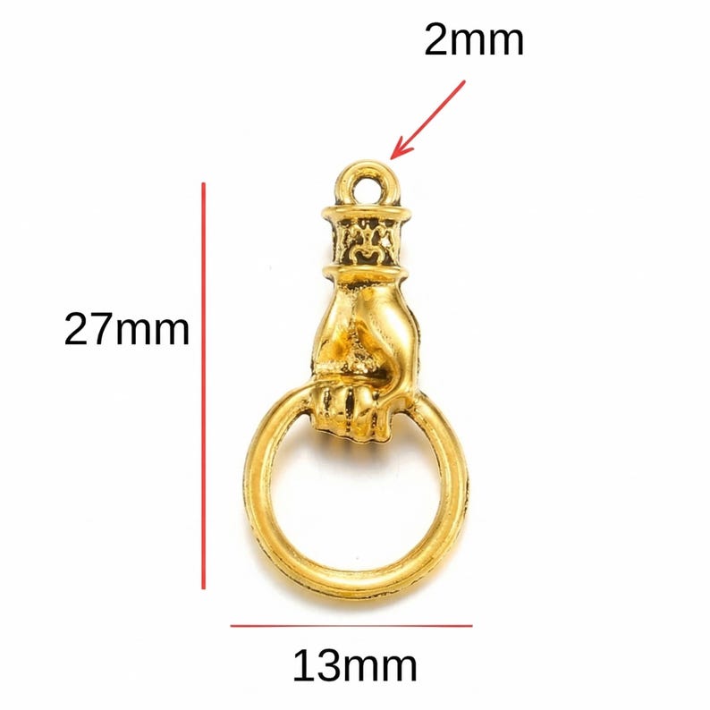 May include: A gold-colored charm shaped like a hand holding a ring. The charm is 27mm long, 13mm wide, and has a 2mm hole at the top. The charm has an antique or vintage aesthetic.