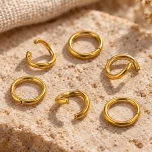 Gold-tone stainless steel open jump rings. Macro detail. 5mm diameter; 0.8mm wire. Buyer pack: 100 pieces.