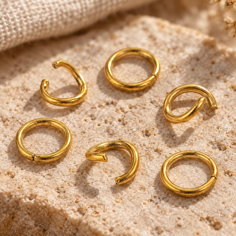 Gold-tone stainless steel open jump rings. Macro detail. 5mm diameter; 0.8mm wire. Buyer pack: 100 pieces.