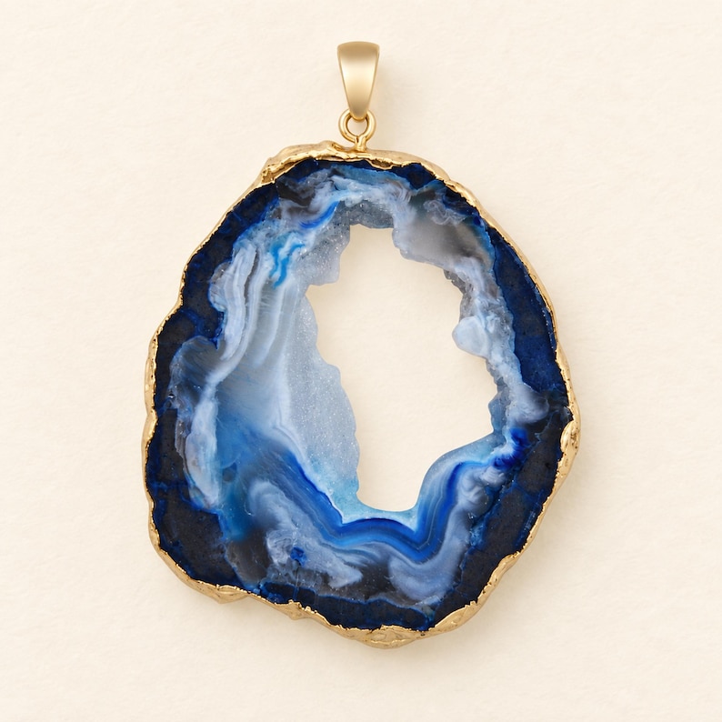 May include: A pendant featuring a slice of blue and white agate stone with a hollow center. The irregular, organic shape of the stone is framed by a textured gold-colored metallic edge and includes a matching gold-colored bail at the top.
