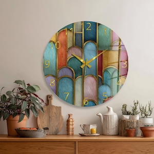 May include: A circular wall clock featuring a colourful geometric pattern of overlapping vertical arches in shades of blue, green, pink, yellow, and orange, outlined in gold. The clock face displays gold numerals and thin gold clock hands.