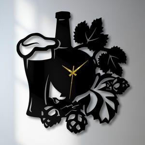 May include: Black wall clock featuring a beer bottle, a pint of beer with foam, and hop leaves. The clock hands are gold. The clock is a decorative item for a bar or kitchen.