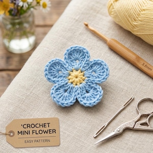 May include: A close-up of a crocheted mini flower with light blue petals and a yellow center. The flower is on a beige linen surface, with a crochet hook, yarn, scissors, and a needle nearby. A tag reads 'CROCHET MINI FLOWER EASY PATTERN'.