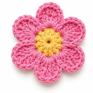 May include: A handmade crochet flower with five pink petals surrounding a yellow center. The flower is made of yarn and has a textured appearance. The craft item is set against a white background.