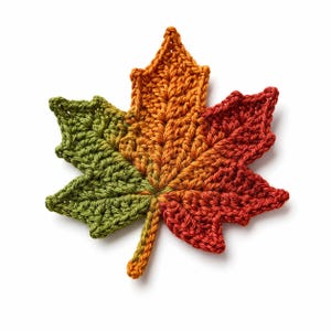 Peut inclure: Une feuille d'érable au crochet présentant un dégradé de couleurs passant du vert olive sur le côté gauche à l'orange au centre et au rouge foncé sur le côté droit, avec une surface en fil texturé et une tige centrale bien définie.