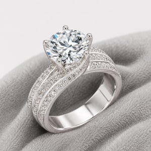 May include: A silver-coloured ring featuring a large, round, faceted clear centre stone held by four prongs. The band is split into three distinct, overlapping sections, each encrusted with numerous small, sparkling clear stones.