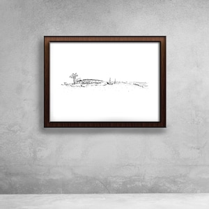 May include: A framed black and white sketch of a landscape scene. The artwork, set within a dark brown wooden frame, depicts a tree, a structure, and other elements, possibly a shoreline. The image is mounted on a gray textured wall.