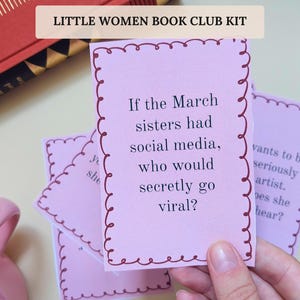 Op de afbeelding: Een set lichtroze rechthoekige kaarten met een donkerrode geschulpte rand. De middelste kaart bevat de zwarte tekst: If the March sisters had social media, who would secretly go viral? De kaarten maken deel uit van een Little Women Book Club Kit.