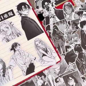 Op de afbeelding: Een verzameling zwart-wit stickers in anime-stijl met verschillende personages en scènes. De stickers zijn geplaatst op een notitieboek met een rode rand. Sommige stickers hebben Japanse tekst.