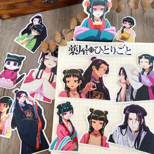 May include: A selection of anime-style stickers depicting characters in traditional Asian clothing. The stickers display characters with detailed facial features and vibrant outfits. The text "薬屋のひとりごと" is present on a notepad.