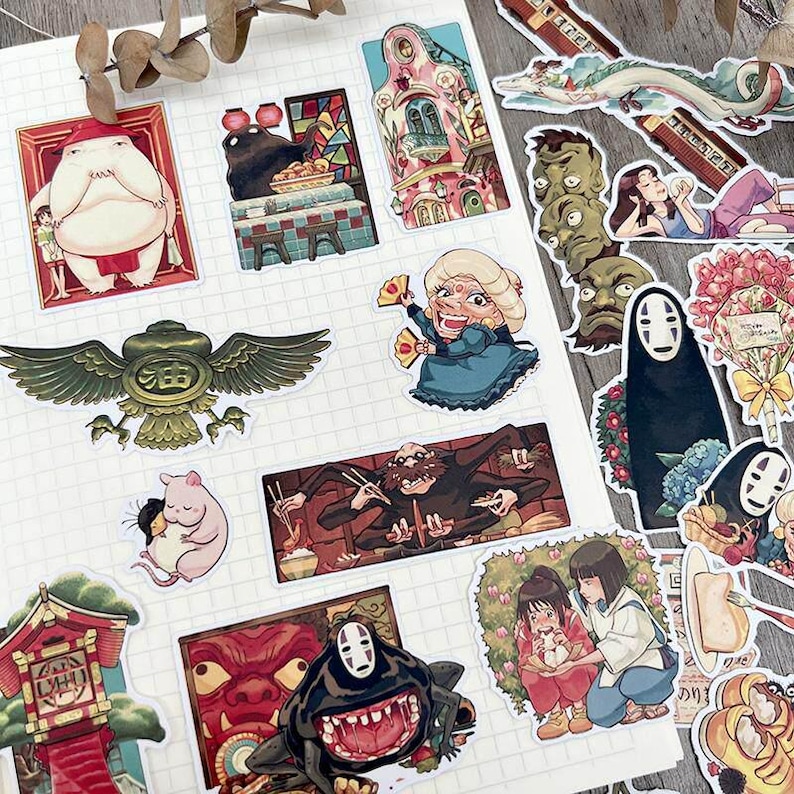 May include: A collection of colorful stickers featuring characters and scenes from an animated film. The stickers include images of a large, round character, a dragon, and a masked figure. The stickers are arranged on a white, lined surface.