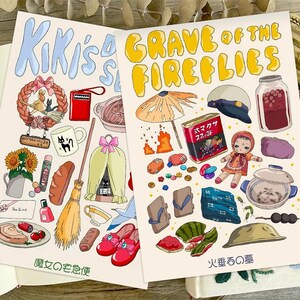 Peut inclure: Deux impressions d'art illustr&eacute;es avec des dessins color&eacute;s d'objets et de texte. L'une des impressions dit "Kiki's Delivery Service" et l'autre dit "Grave of the Fireflies" en lettres jaunes. Les impressions pr&eacute;sentent une vari&eacute;t&eacute; d'objets et d'illustrations.