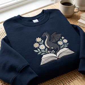 Felpa ricamata con drago e margherite, regalo ideale per gli amanti dei libri fantasy.