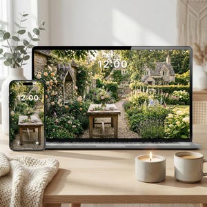 Puede incluir: Un ordenador portátil y un smartphone muestran una escena de jardín con una mesa de madera, flores y una casa de piedra. La hora 12:00 se muestra en ambas pantallas. Una vela encendida y una taza de café están sobre una mesa de madera.