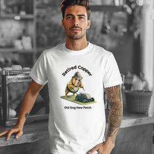 Könnte beinhalten: Ein weißes T-Shirt mit einer Grafik eines Bulldogs, der einen Hut trägt und einen Rasenmäher über eine Grasfläche schiebt. Der Text über dem Hund lautet "Retired Copper" und der Text unter dem Hund "Old Dog New Patch" in schwarzer Schrift.