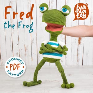 May include: A green crocheted frog puppet with large blue and white eyes, an open mouth, and a striped shirt. The puppet is labeled "Fred the Frog" and includes a "Crochet PDF Pattern" graphic.