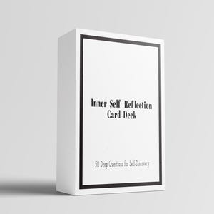 May include: A white rectangular card deck box featuring a black border. The text on the front reads Inner Self Reflection Card Deck and 50 Deep Questions for Self-Discovery in a black serif font. The box is oriented vertically on a plain surface.