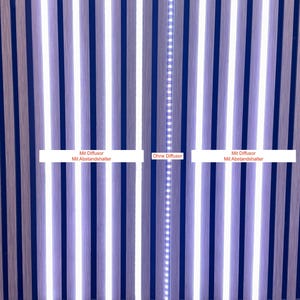 Könnte beinhalten: Vertikale Holzpaneele in Blau- und Grautönen, mit hellen weißen LED-Leuchten dazwischen. Das Bild enthält Text in weißen Rechtecken: "Mit Diffusor Mit Abstandshalter" und "Ohne Diffusor".