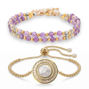 May include: Two bracelets. The top bracelet features rows of purple beads, gold beads, and silver beads. The bottom bracelet is gold with a round pendant featuring a white design and clear stones around the edge. The bottom bracelet has a sliding clasp.