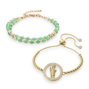 May include: Two bracelets. The top bracelet features green beads with gold and silver accents. The bottom bracelet is gold-toned with a circular pendant of a religious figure surrounded by clear crystals. The bracelet has a sliding clasp.