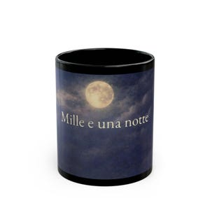 Può includere: Tazza da caffè nera con un design a cielo notturno. La tazza presenta una luna piena, nuvole e il testo italiano "Mille e una notte" in bianco. La tazza ha un bordo e una base neri.