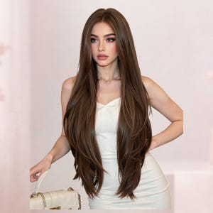 May include: A woman with long, layered brown hair and a white dress. She is holding a white purse with a gold chain. The background is a soft pink with decorative elements.