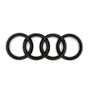 May include: Black Audi emblem featuring four interlocking rings. The rings are a solid, matte black color, set against a clean white background. The design is a well-known automotive logo.