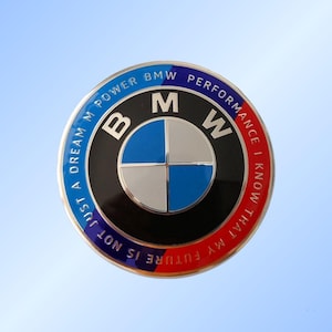 May include: A round BMW emblem with a black border and a blue, white, and black center. The words "BMW Power Performance" and "Just a dream, my future is not, I know that" are written around the edge in blue and red.