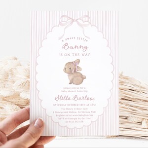 May include: A baby shower invitation with a pink and white striped background. The invitation features a watercolor illustration of a bunny with a pink bow. Text includes "a sweet little Bunny is on the way" and event details.