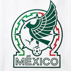 Pu&ograve; includere: Una t-shirt bianca con un logo grafico raffigurante un'aquila verde stilizzata con le ali spiegate, posizionata sopra un pallone da calcio. Il design &egrave; racchiuso in una cornice circolare con accenti rossi e verdi e la parola M&Eacute;XICO in grassetto.