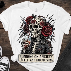 May include: White t-shirt featuring a skull with roses, holding a coffee drink. The skull wears a leather jacket and is surrounded by lightning bolts. Text on the shirt reads: 'RUNNING ON ANXIETY, COFFEE, AND BAD DECISIONS.'