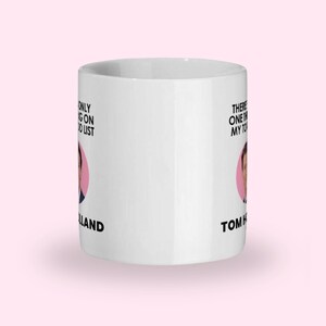 May include: White ceramic mug with the text "There's only one thing on my to-do list" and "Tom Holland". The mug features a pink circle with a picture of Tom Holland.