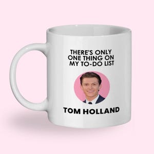 May include: White ceramic mug with the text "THERE'S ONLY ONE THING ON MY TO-DO LIST" and the name "TOM HOLLAND" below a photo of Tom Holland in a pink circle.