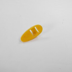 May include: A yellow plastic finger pick with a rectangular opening in the center.