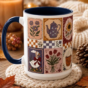 May include: A white ceramic mug with a dark blue interior and handle, featuring a patchwork-style design of rectangular illustrations including a goose with a red bow, a teapot, a sunflower, tulips, a coffee cup, and various floral patterns.