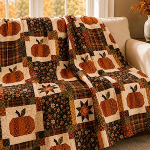 May include: A patchwork quilt featuring a repeating pattern of orange pumpkins, dark floral blocks, and plaid squares in shades of brown, green, and cream. The textile displays a grid design with alternating pumpkin motifs and star shapes.