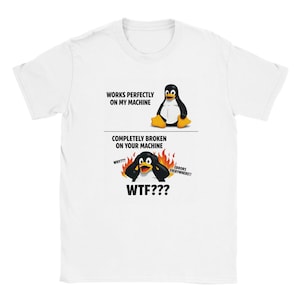 May include: White t-shirt with a cartoon penguin graphic. The design shows the penguin in two states, with text reading "WORKS PERFECTLY ON MY MACHINE" and "COMPLETELY BROKEN ON YOUR MACHINE." Additional text includes "WHY???", "WTF???", and "ERRORS EVERYWHERE!!".